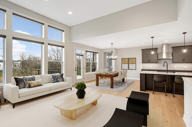 living room with light wood-type flooring, sink, and a chandelier