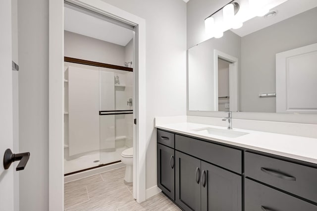 bathroom with vanity, toilet, and a shower with door