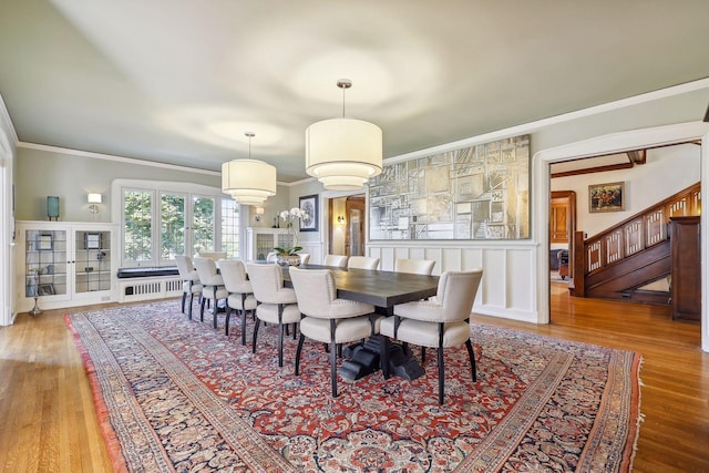 dining area with radiator, crown molding, and wood-type flooring