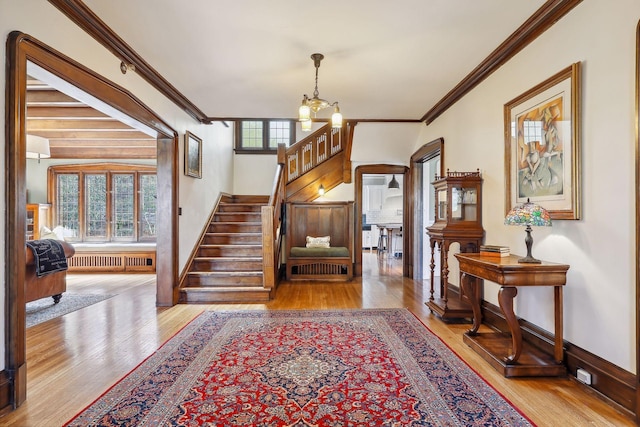 foyer entrance with light hardwood / wood-style floors, radiator, crown molding, and a notable chandelier