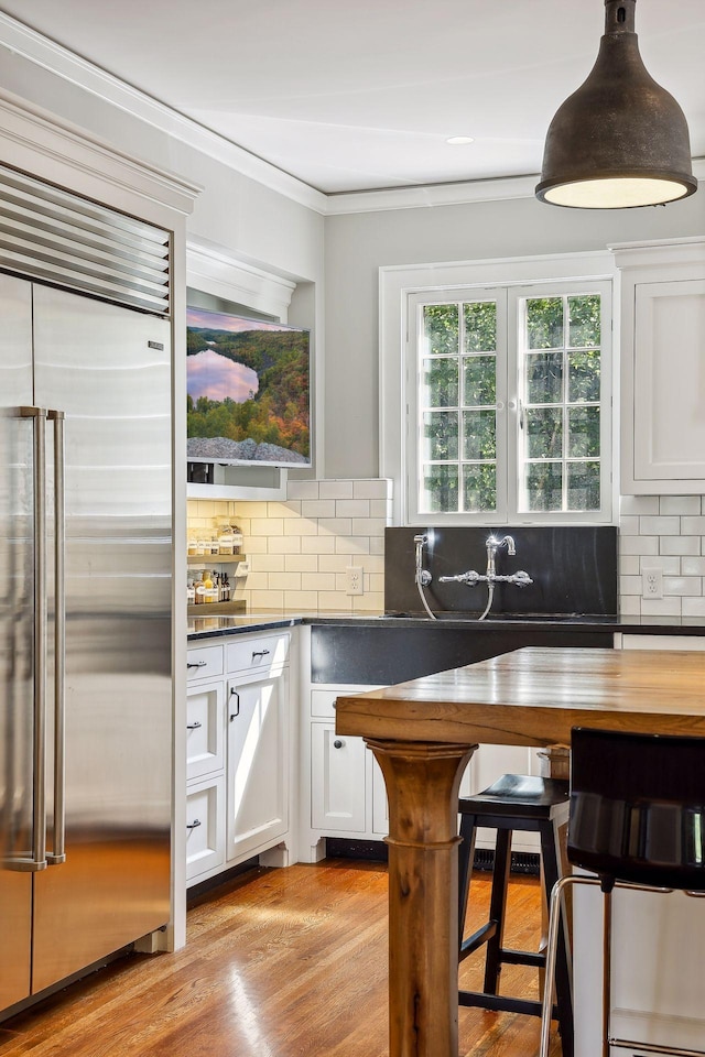 kitchen with white cabinets, tasteful backsplash, and built in fridge