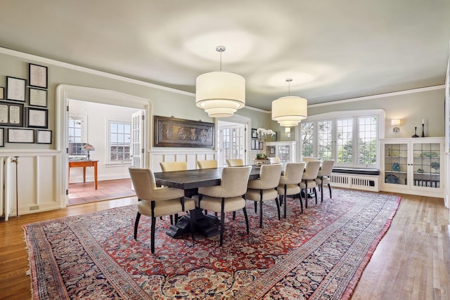 dining area featuring wood-type flooring, ornamental molding, and radiator