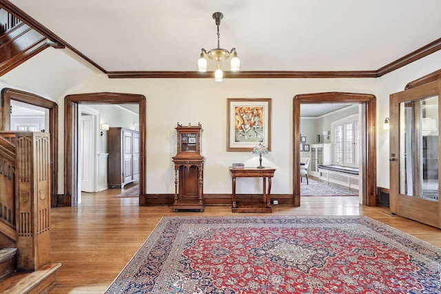 entryway featuring hardwood / wood-style floors, crown molding, and an inviting chandelier