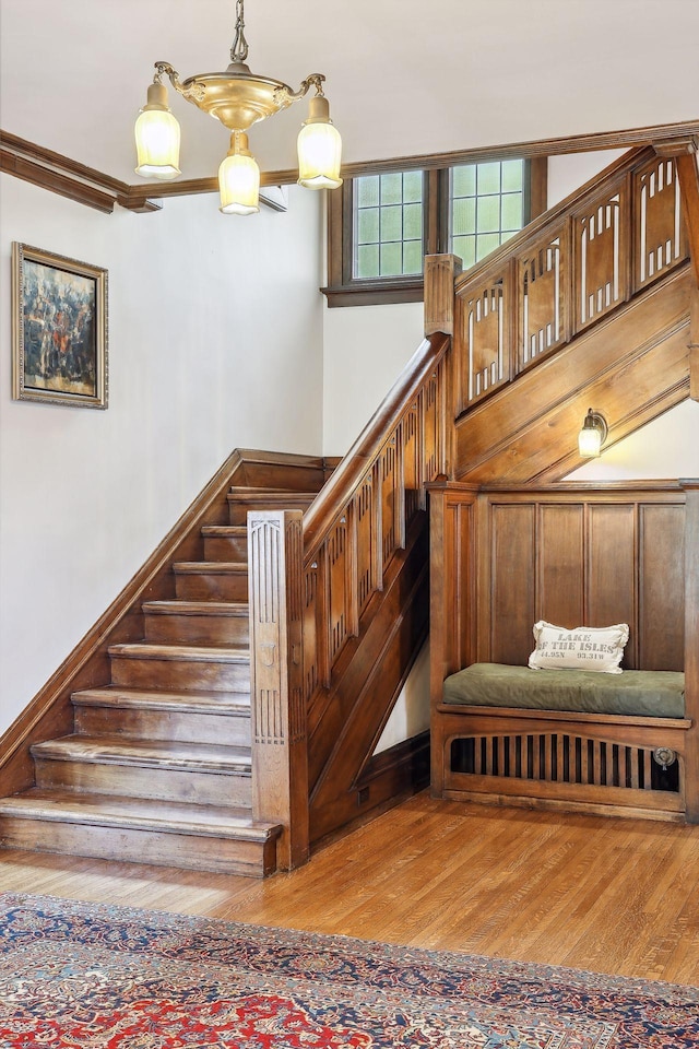 stairs with hardwood / wood-style floors and an inviting chandelier