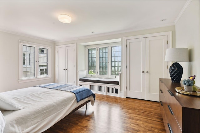 bedroom featuring dark hardwood / wood-style floors, crown molding, radiator, and multiple closets