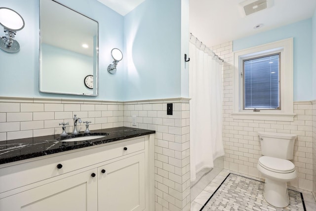 bathroom featuring vanity, tile patterned flooring, toilet, tile walls, and walk in shower