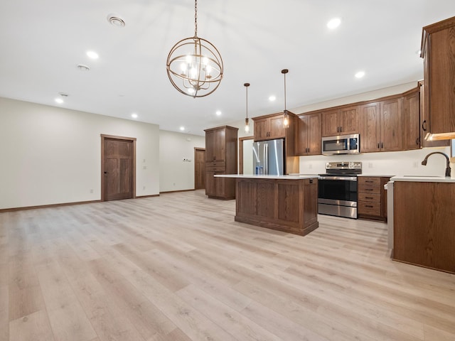 kitchen featuring stainless steel appliances, light hardwood / wood-style floors, a center island, an inviting chandelier, and hanging light fixtures