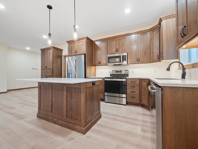 kitchen featuring hanging light fixtures, light hardwood / wood-style flooring, appliances with stainless steel finishes, and a center island