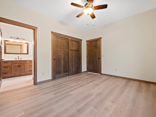 unfurnished bedroom featuring light hardwood / wood-style floors, sink, ensuite bathroom, ceiling fan, and a closet