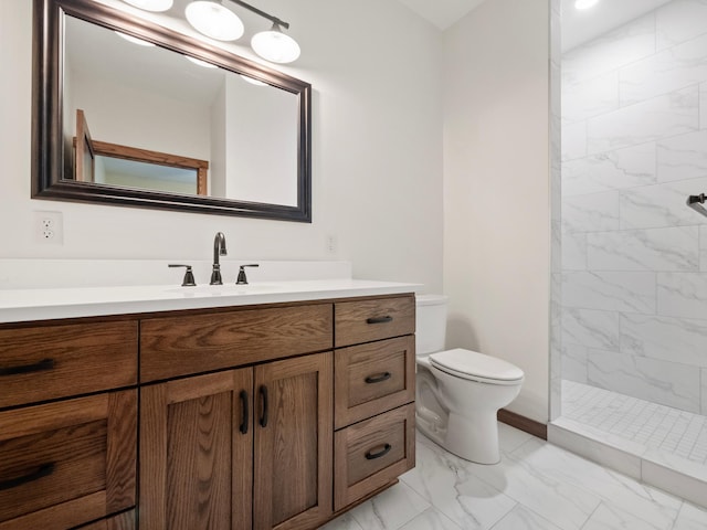 bathroom with a tile shower, vanity, and toilet