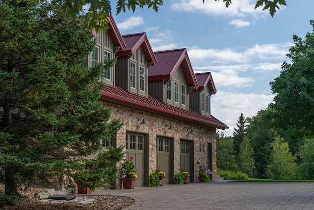 19752 Halwood Rd, Glenwood Twp, MN 56334 - view of side of home featuring stone siding, a standing seam roof, metal roof, curved driveway, and board and batten siding