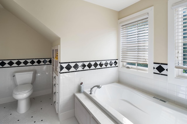 19752 Halwood Rd, Glenwood Twp, MN 56334 - bathroom with tile walls, a garden tub, toilet, wainscoting, and tile patterned floors