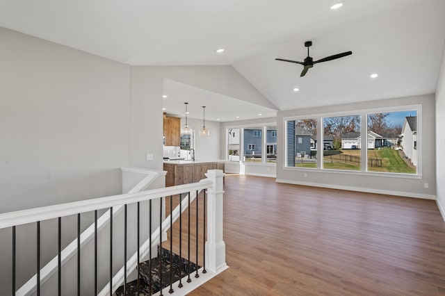 corridor with hardwood / wood-style floors, lofted ceiling, sink, and an inviting chandelier