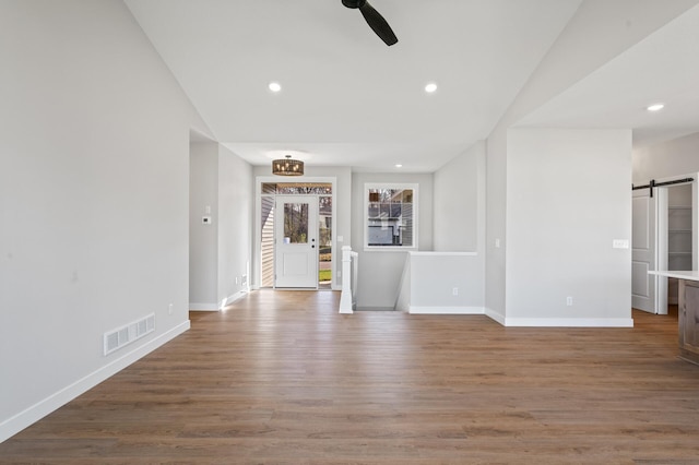 unfurnished living room with a barn door and hardwood / wood-style flooring