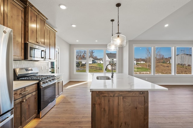 kitchen featuring a center island with sink, light wood-type flooring, sink, and appliances with stainless steel finishes