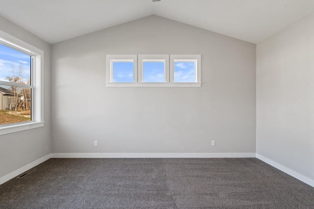 spare room with dark colored carpet and vaulted ceiling