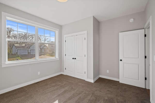 unfurnished bedroom featuring dark carpet and a closet