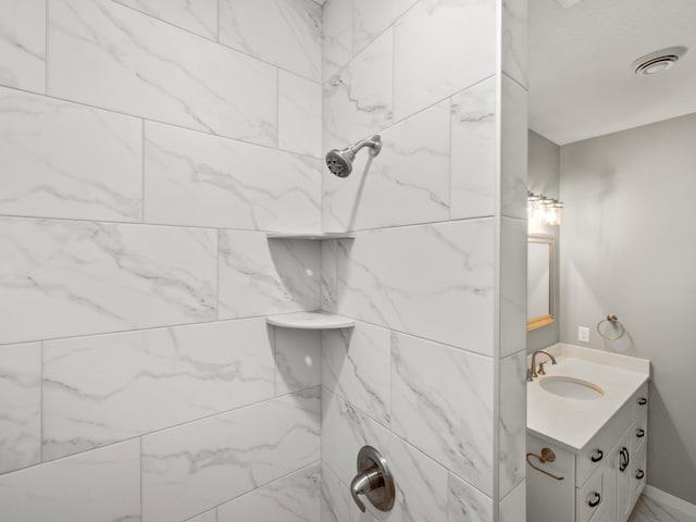 bathroom with vanity and a tile shower