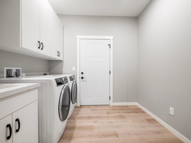 washroom with separate washer and dryer, light hardwood / wood-style flooring, and cabinets