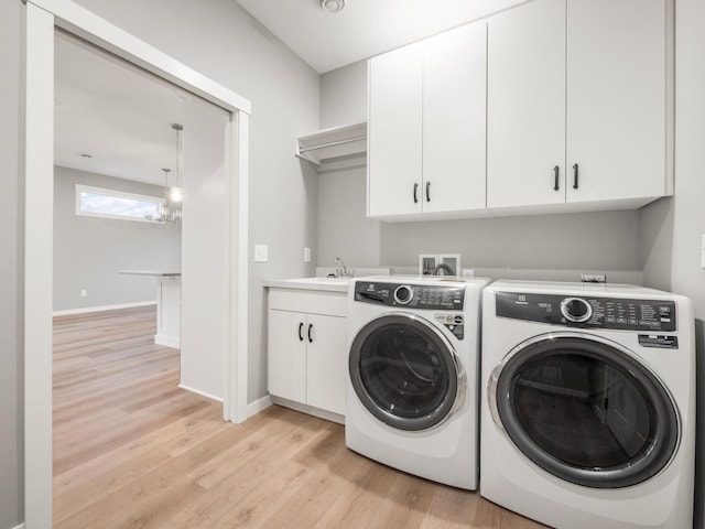 laundry area featuring cabinets, sink, washer and clothes dryer, a notable chandelier, and light wood-type flooring