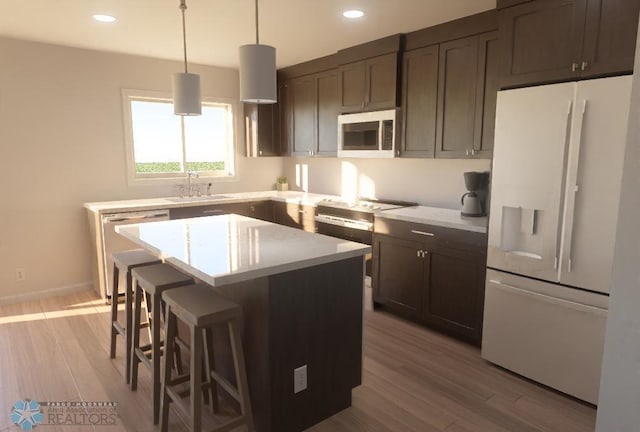 kitchen featuring appliances with stainless steel finishes, sink, pendant lighting, light hardwood / wood-style flooring, and a kitchen island