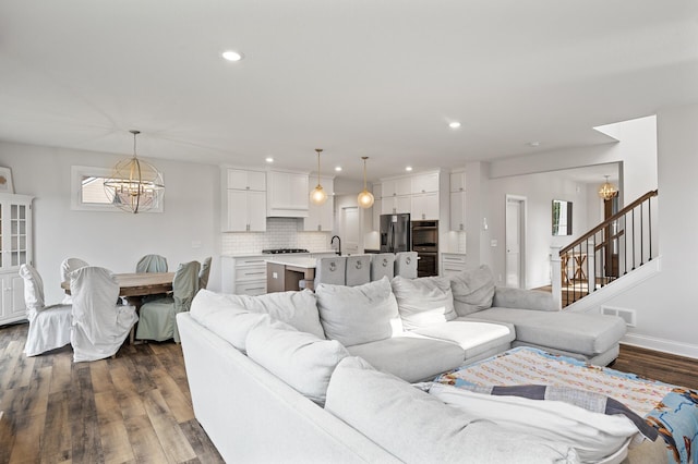 living room with dark hardwood / wood-style flooring, a notable chandelier, and sink