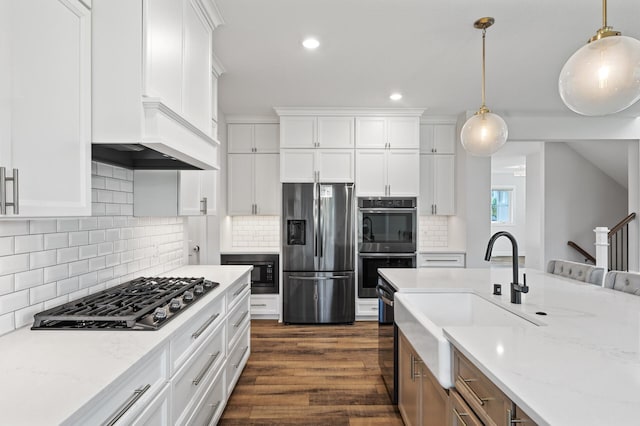 kitchen featuring appliances with stainless steel finishes, decorative light fixtures, white cabinets, dark hardwood / wood-style flooring, and light stone countertops