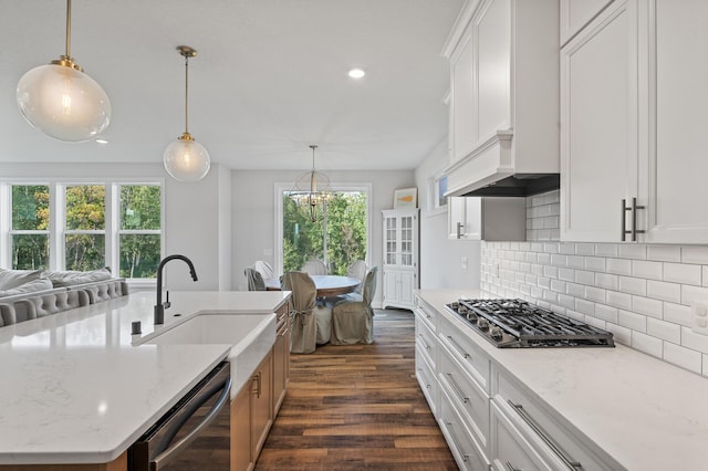 kitchen featuring sink, appliances with stainless steel finishes, white cabinetry, a kitchen island with sink, and light stone counters