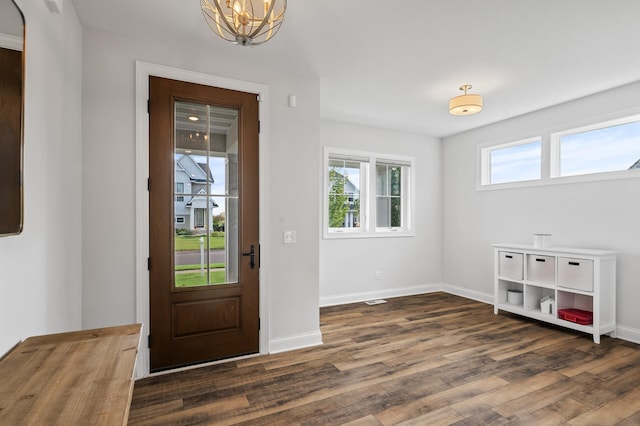 entryway with an inviting chandelier and dark hardwood / wood-style flooring