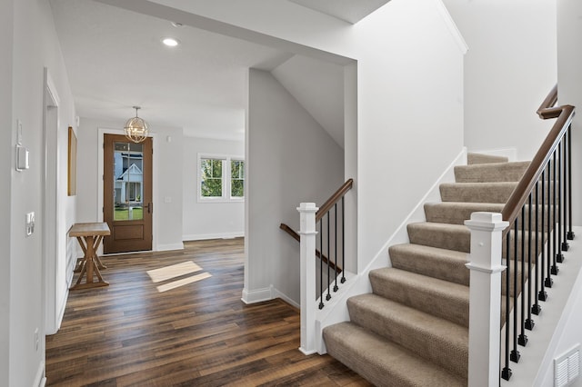 stairway featuring a notable chandelier and wood-type flooring