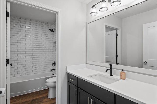 full bathroom featuring tiled shower / bath, wood-type flooring, toilet, and vanity