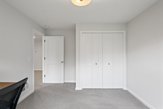 unfurnished bedroom with light carpet and a closet