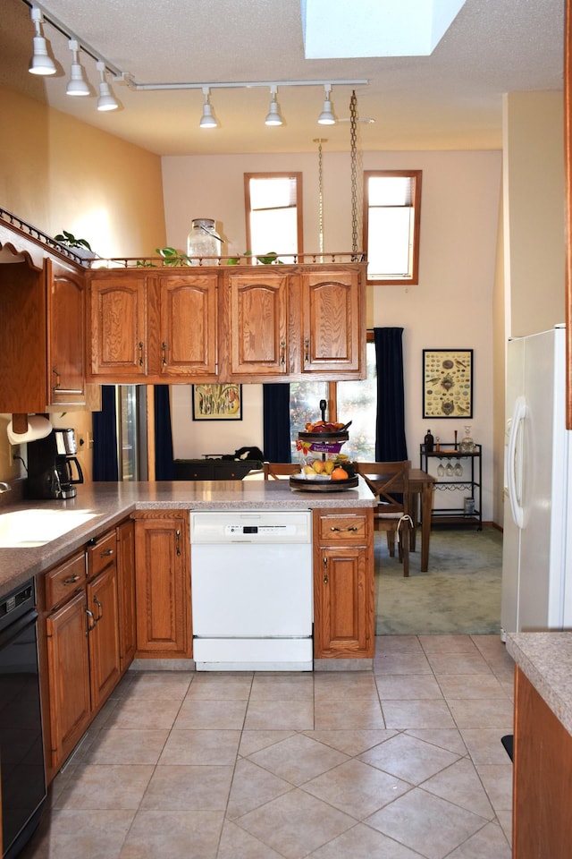 kitchen with kitchen peninsula, sink, light tile patterned floors, and white appliances