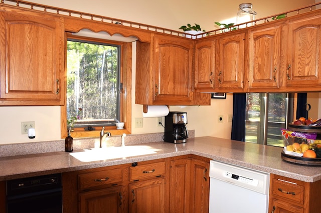2935 Acorn Ln NE, Bemidji, MN 56601 - kitchen with dishwasher, a sink, brown cabinetry, a peninsula, and light countertops