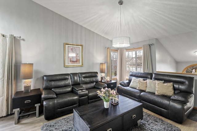 living room featuring an inviting chandelier, light hardwood / wood-style floors, and vaulted ceiling