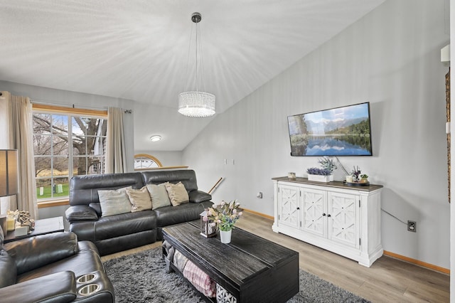 living room with light hardwood / wood-style floors, lofted ceiling, and a notable chandelier