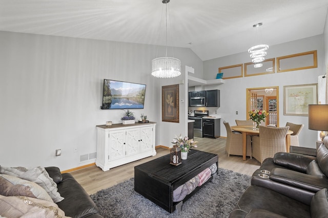 living room featuring hardwood / wood-style floors, vaulted ceiling, and a notable chandelier