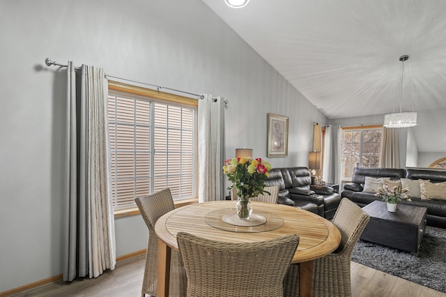 dining area with high vaulted ceiling, light hardwood / wood-style floors, and an inviting chandelier