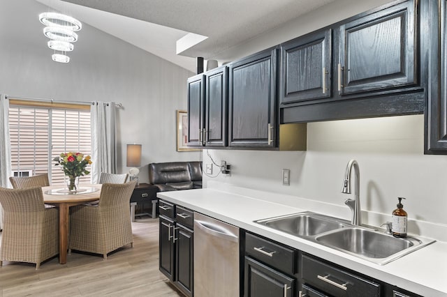 kitchen with light wood-type flooring, stainless steel dishwasher, vaulted ceiling, sink, and a chandelier