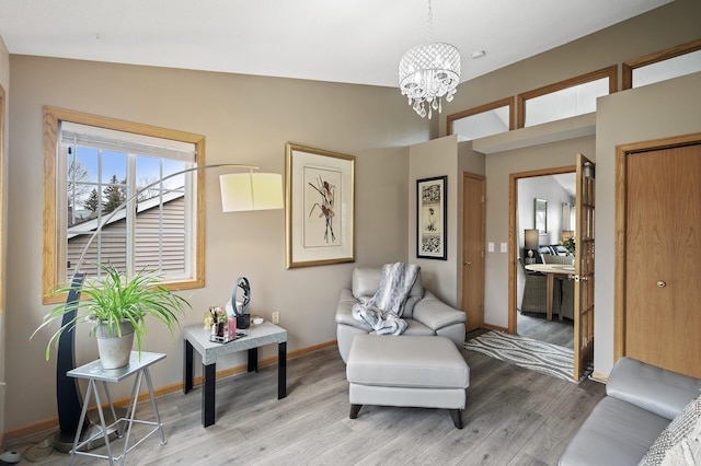 living area with an inviting chandelier, light hardwood / wood-style flooring, and lofted ceiling