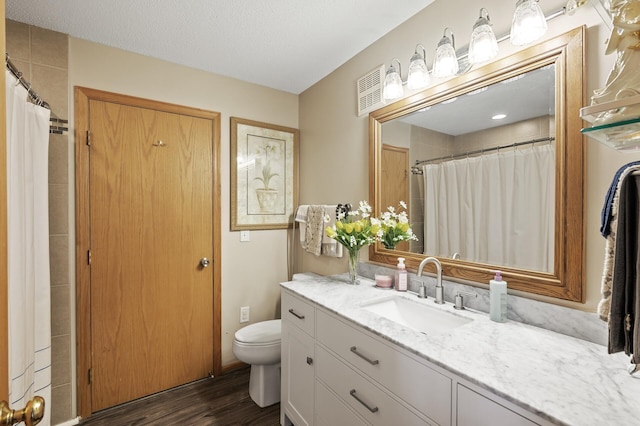 bathroom with vanity, toilet, wood-type flooring, and a textured ceiling