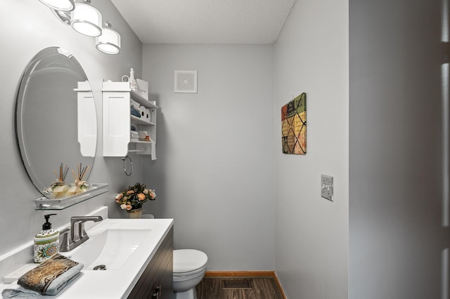 bathroom featuring vanity, a textured ceiling, hardwood / wood-style flooring, and toilet