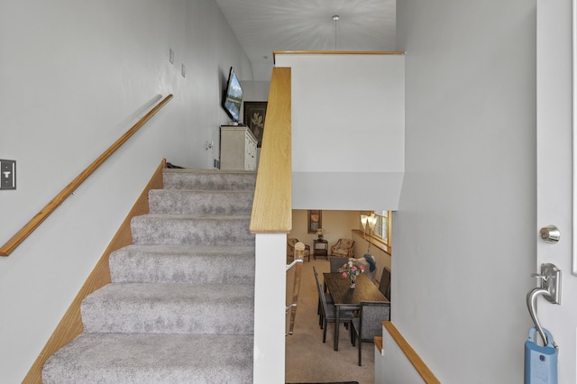 stairway with carpet flooring and an inviting chandelier