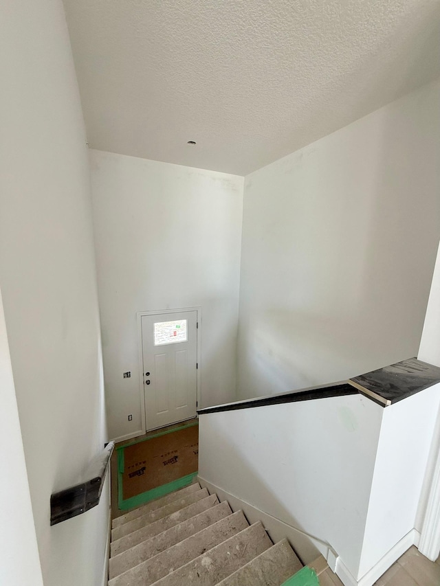 stairway featuring a textured ceiling