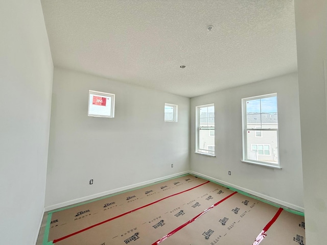 unfurnished room featuring plenty of natural light and a textured ceiling