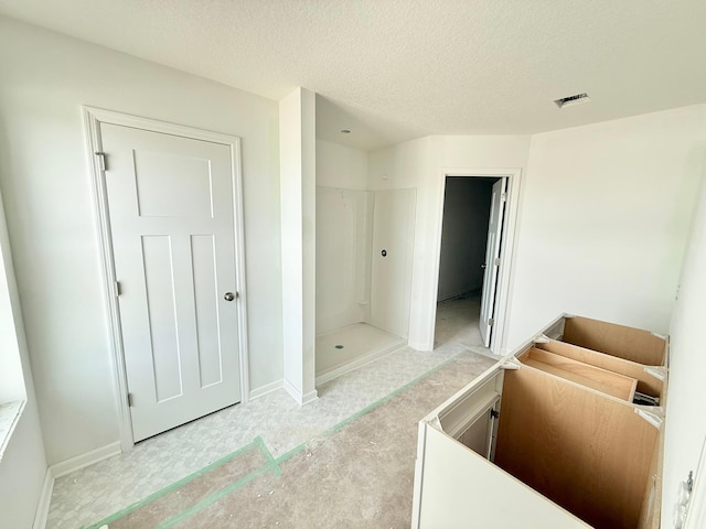 bathroom featuring a shower and a textured ceiling