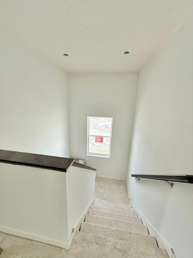 stairway featuring a textured ceiling