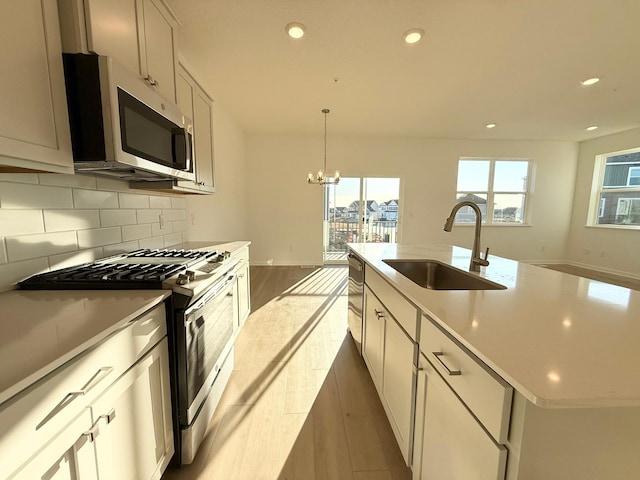 kitchen featuring tasteful backsplash, wood finished floors, stainless steel appliances, a sink, and recessed lighting