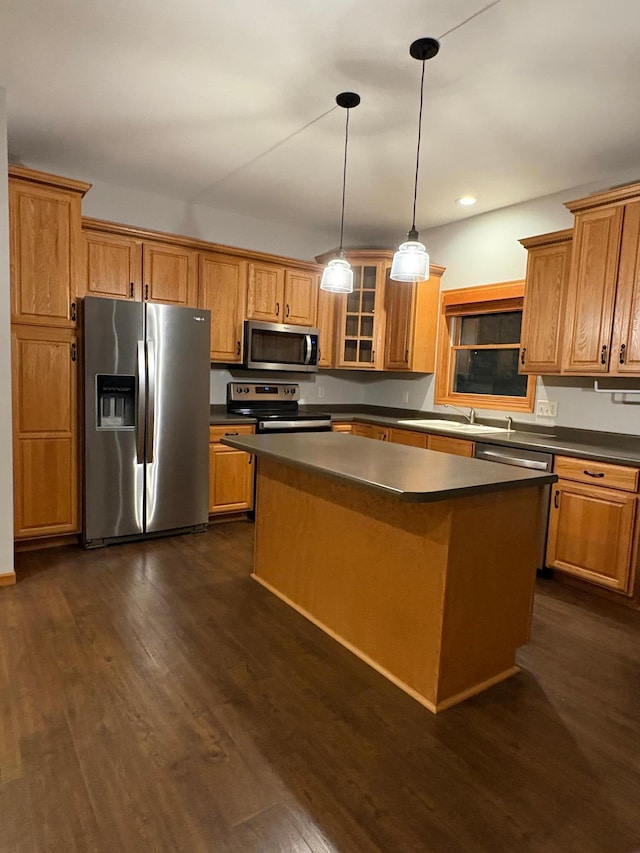 kitchen with stainless steel appliances, dark wood-type flooring, sink, a kitchen island, and pendant lighting