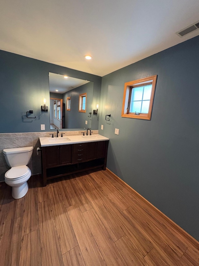 bathroom featuring toilet, vanity, wood-type flooring, and tile walls